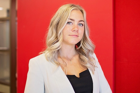 female business student standing in front of red background