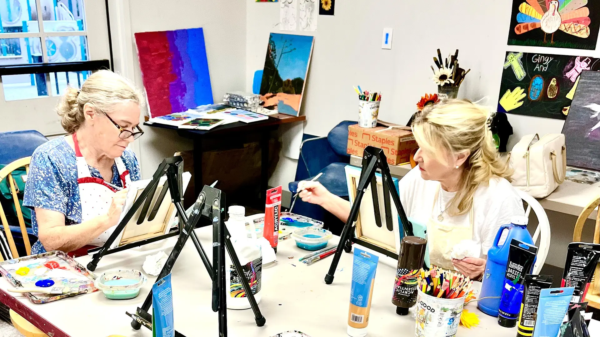 two female adults painting in an art class