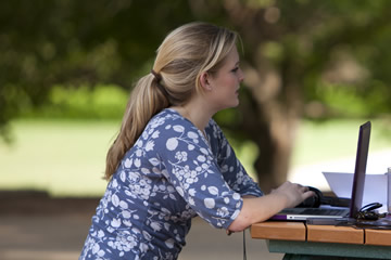 female student studying outside with laptop