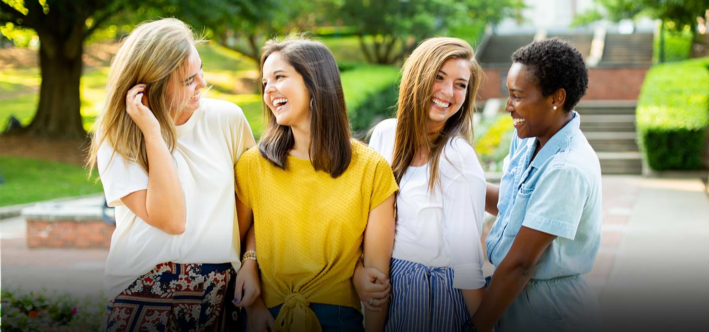 Four female students interlocking arms