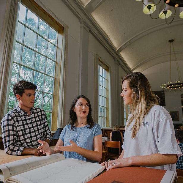 Male and two female students in the library