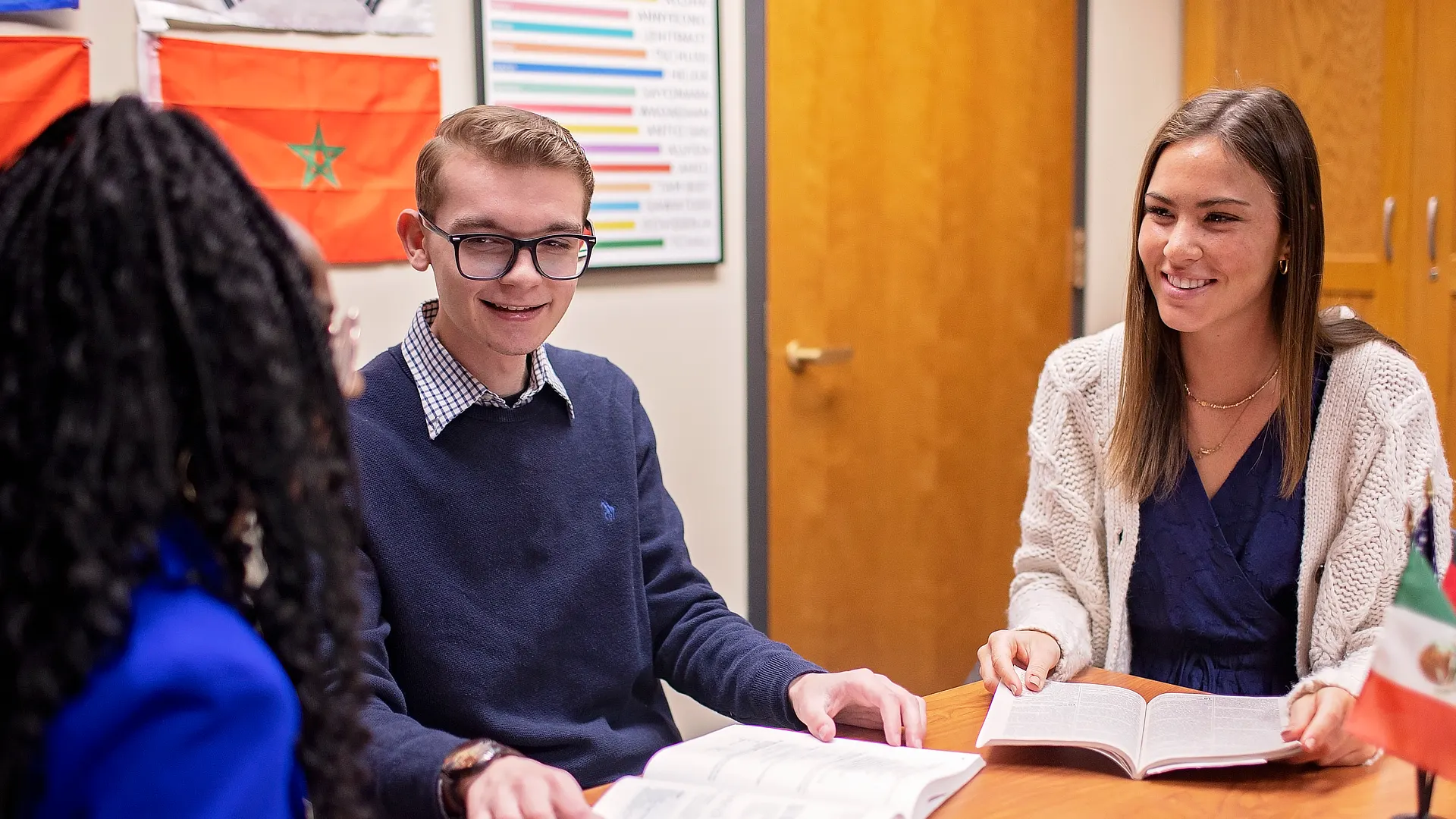 Three Students Reading and Discussing A Book Together