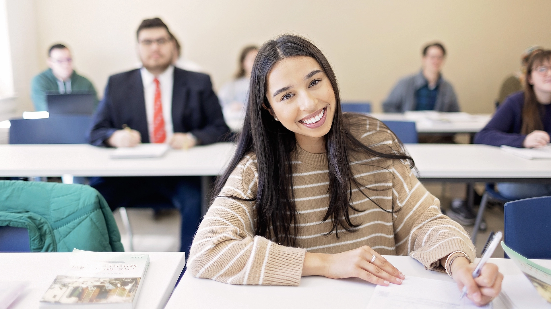 smiling student in class with pen