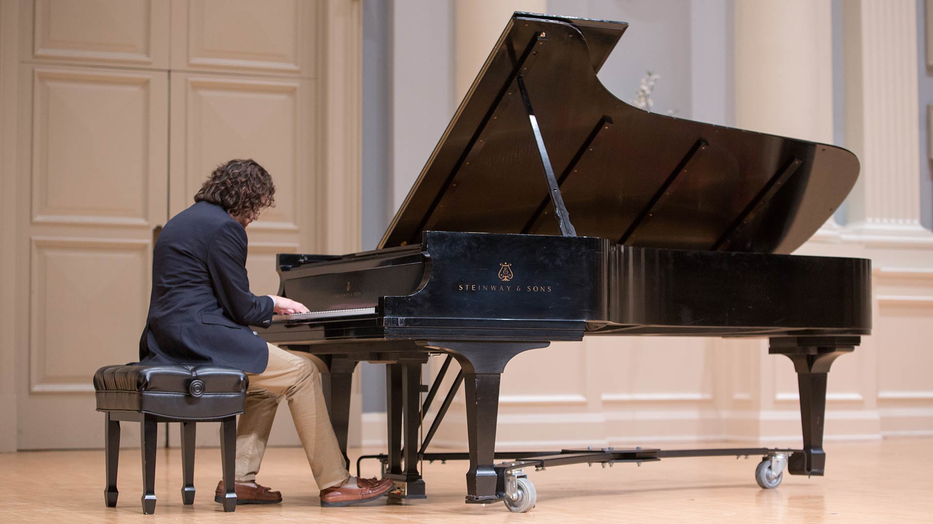 male student playing grand piano