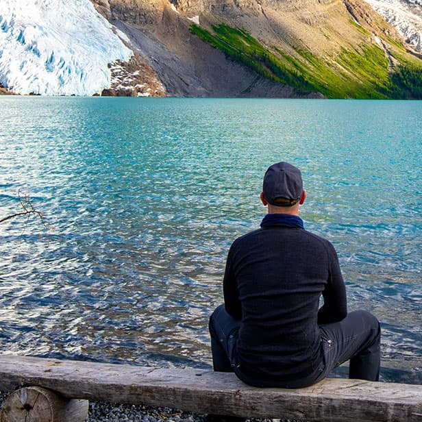 Man contemplating a lake and mountains