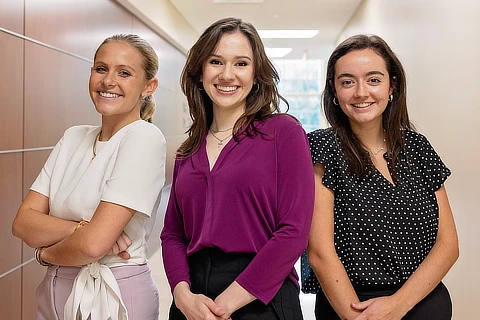 three female business student standing together in the hallway