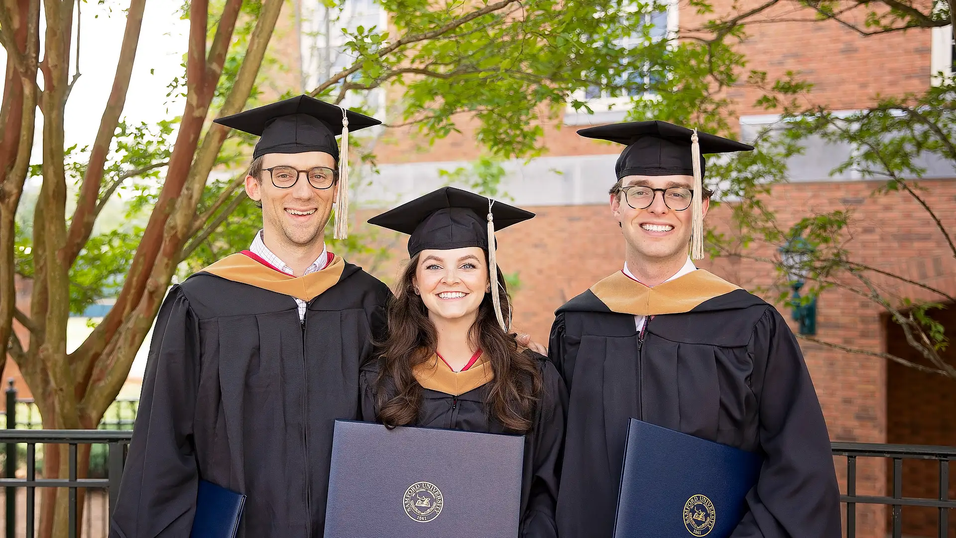 three business students with diplomas