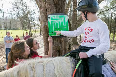 students assisting a boy on a horse