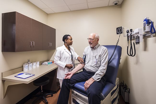 A nursing student examining a patient in the Standardized Patient Exam Room.