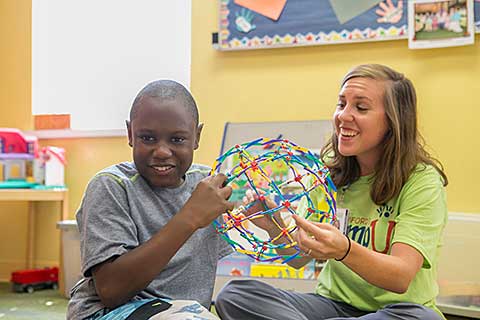 young boy plays with female student