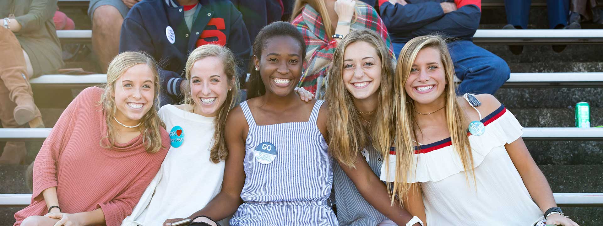 five smiling female students at football game