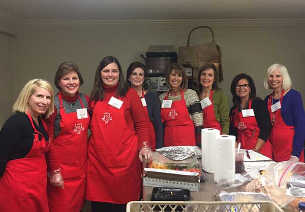 Eight women in red aprons