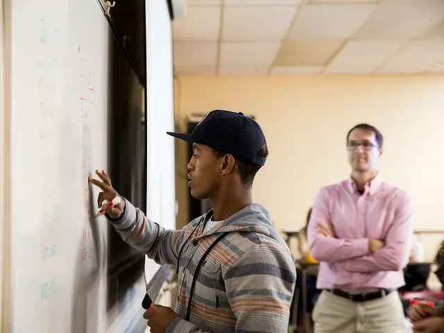 black student writes on whiteboard SD11184645