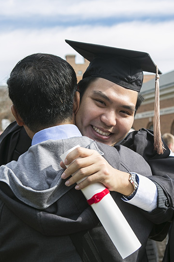 male graduate hugging