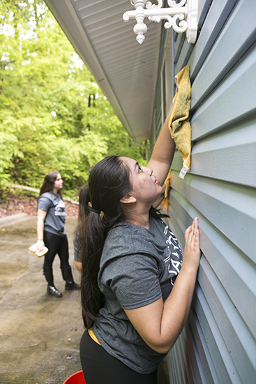 student cleaning siding
