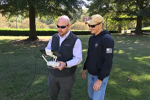 Two men in field with device