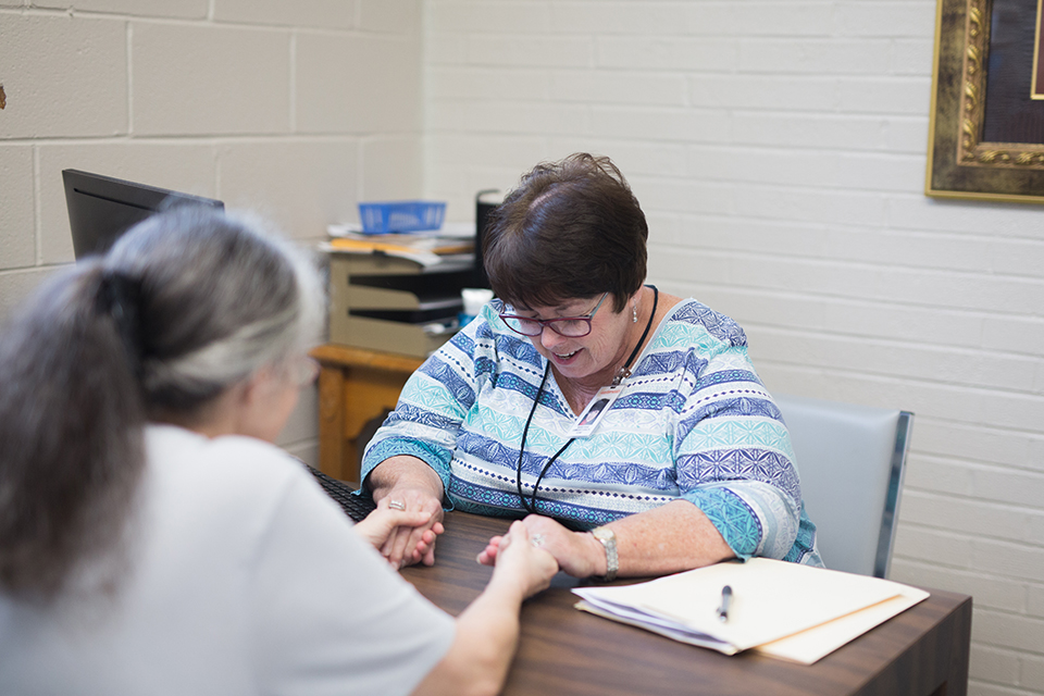 Debbie Duke praying with a patient at the clinic.