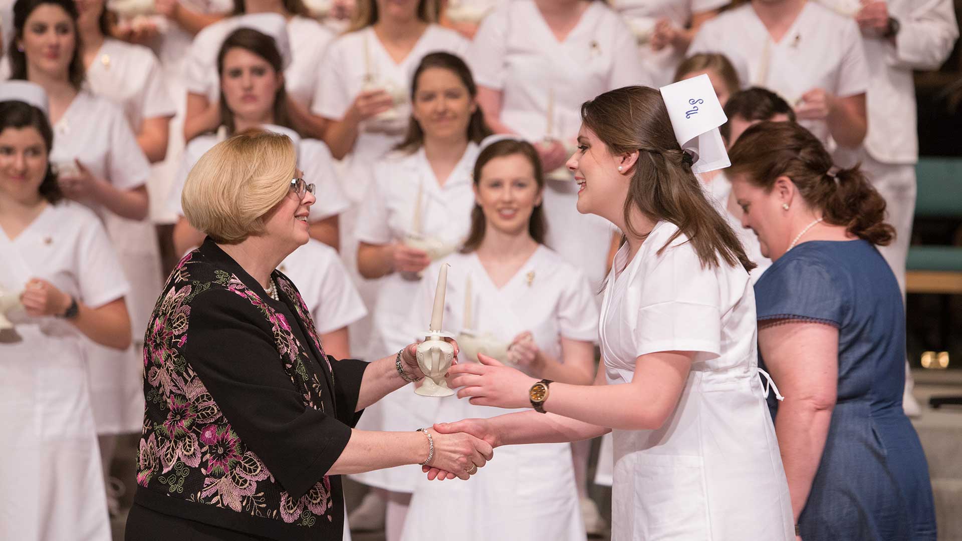 female nursing student accepts lamp from dean sanders