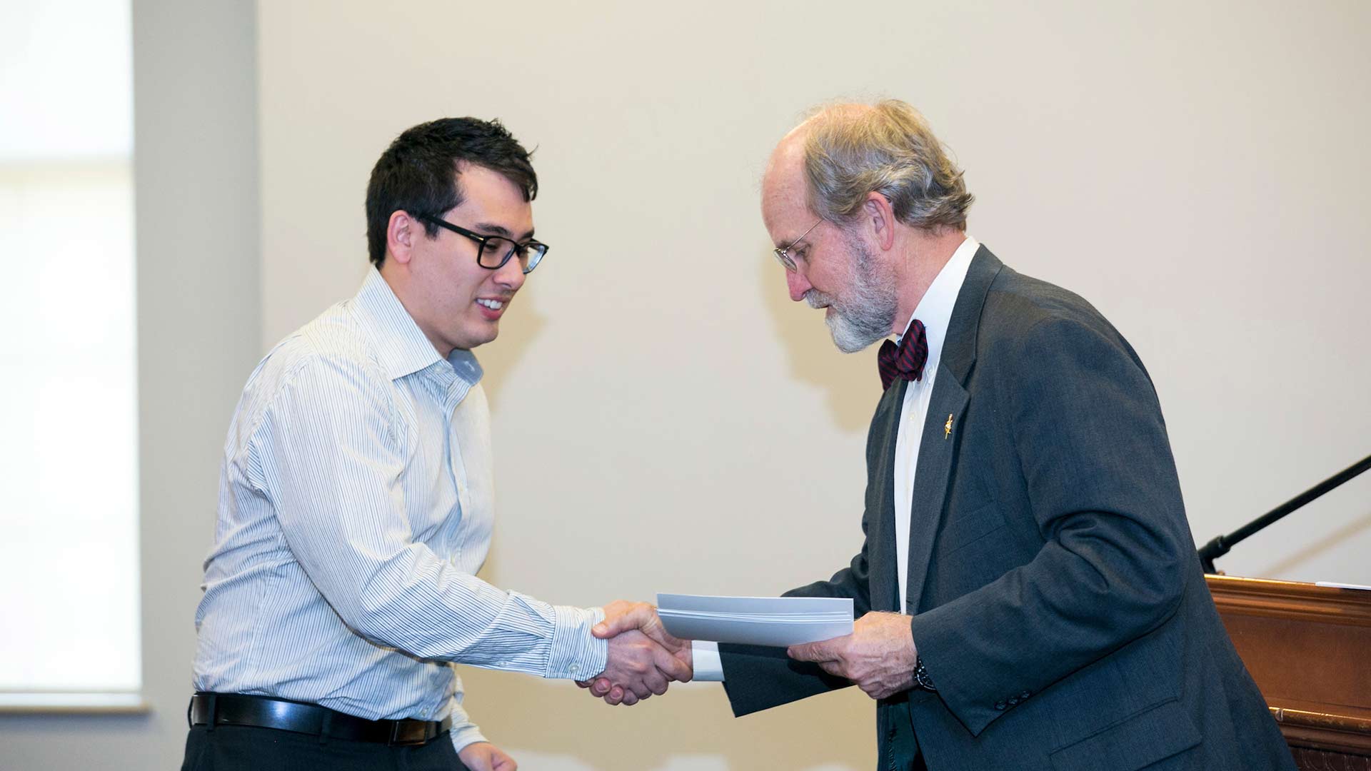 male student receiving certificate from professor