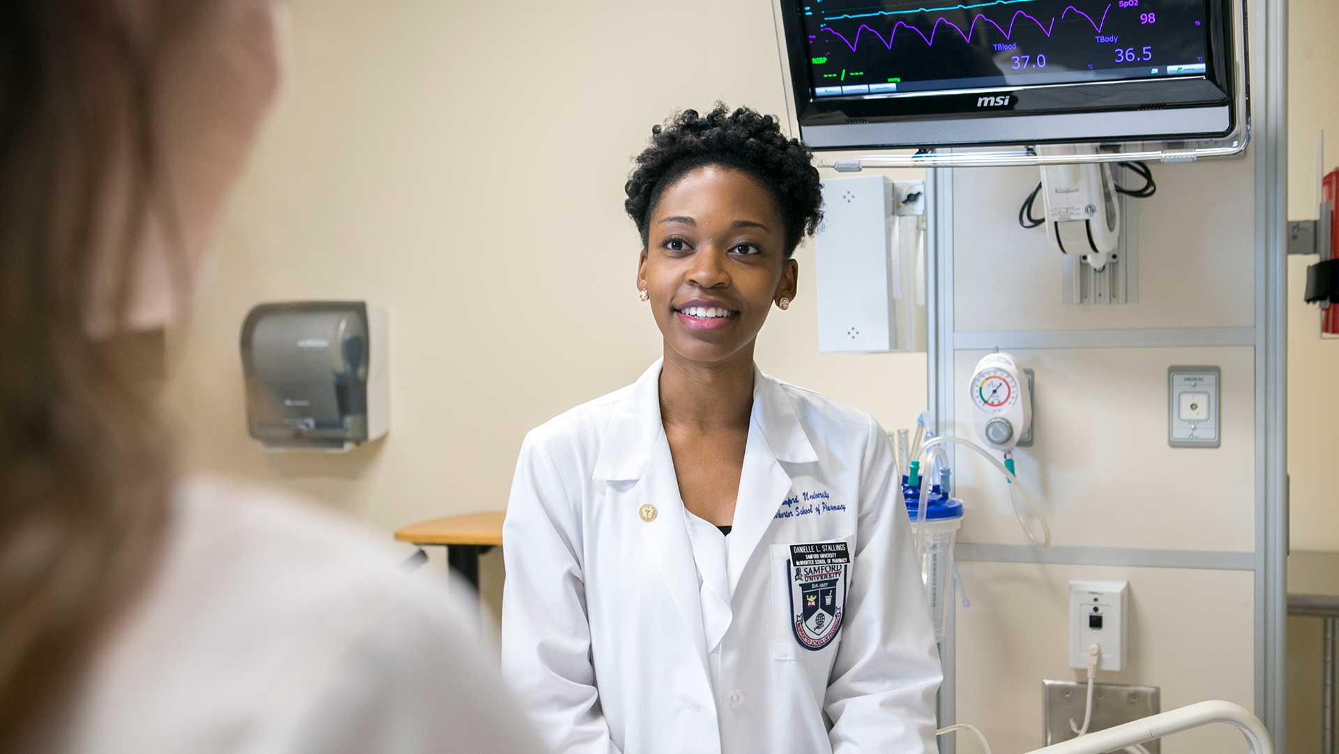 Black female pharmacy student at patient bedside