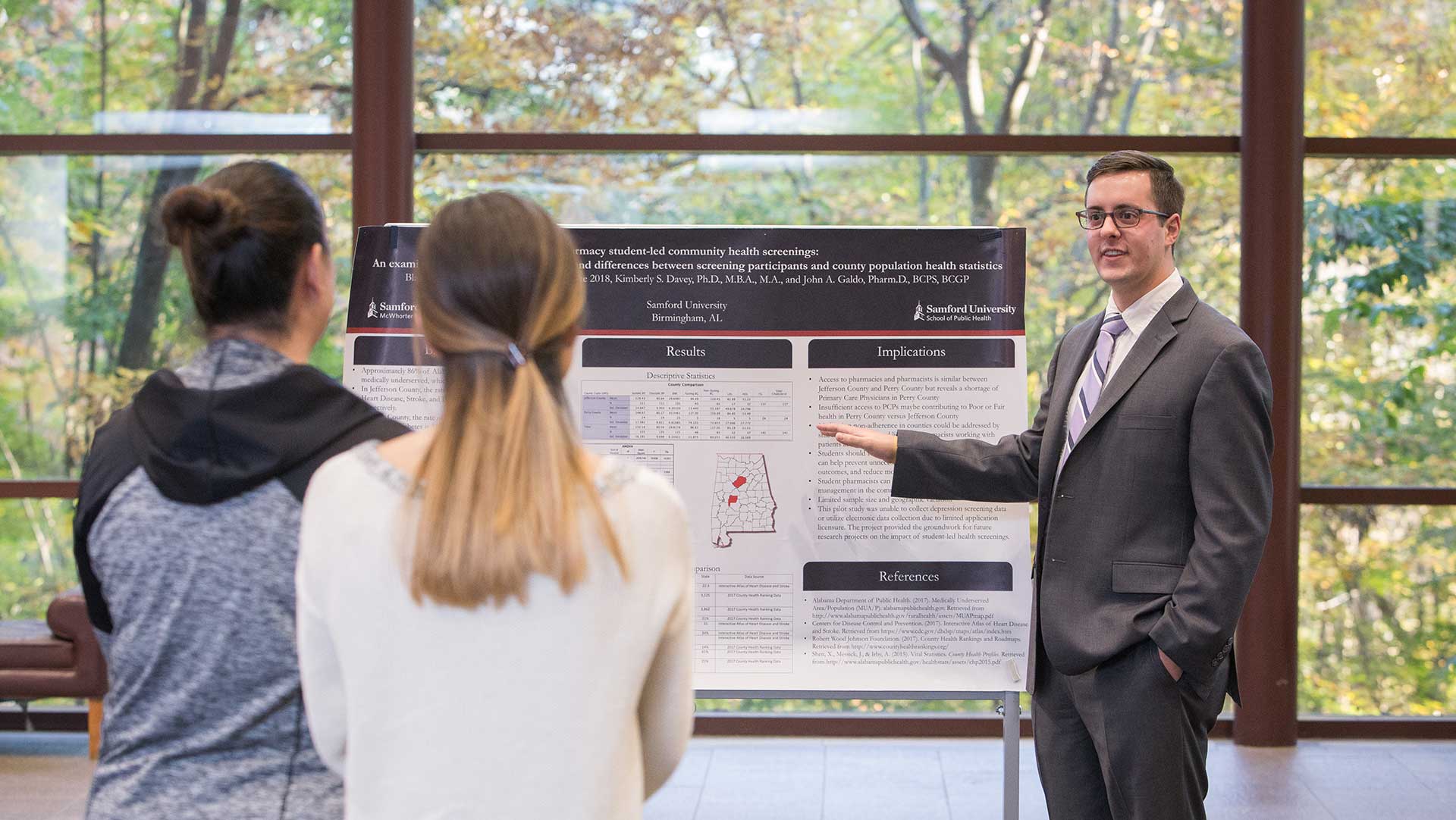 white male student explaining poster to female students