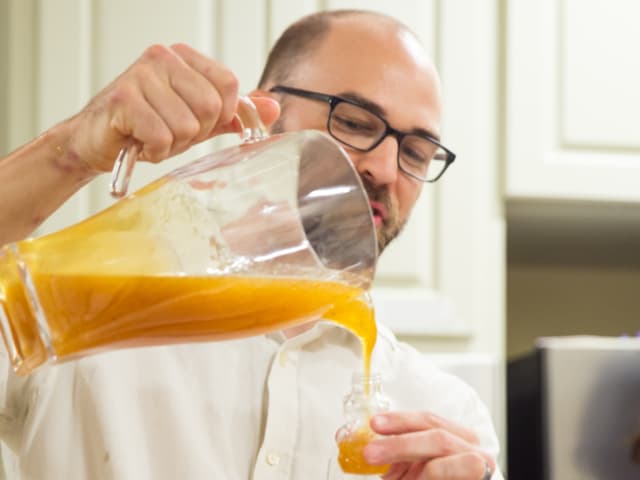 man pouring healthful orange liquid